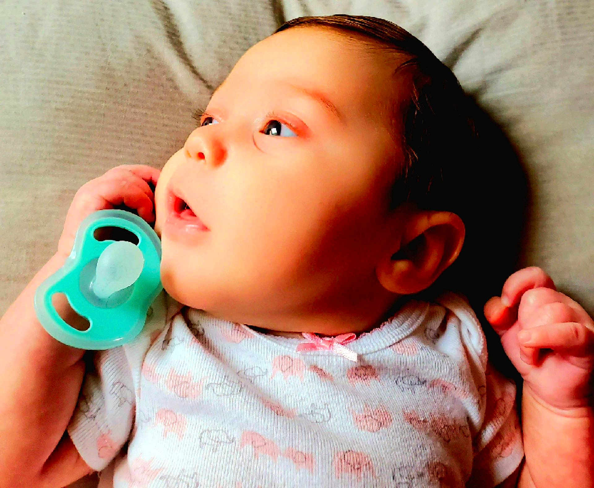 Jordyn-Kate joined the competition — help win amazing prizes! baby, infant, pacifier, onesie, clothing, hand, face, skin, expression, lying_down, soft_surface, curious, child, newborn, portrait, cute, pink_bow, animal_prints, closeup, head