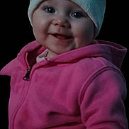 Athena joined the competition — help win amazing prizes! baby, black_background, child, closeup, clothing, cute, face, happy, hat, headwear, hoodie, indoor, infant, knit_hat, person, pink_jacket, portrait, smile, warm_clothing, young_child