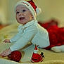 Athena joined the competition — help win amazing prizes! baby, blanket, celebration, child, christmas, cute, face, festive, happy, holiday, holiday_decoration, indoor, infant, lying_down, ornament, red_skirt, santa_hat, smiling, toy, white_outfit