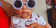 Seyda Melody is registered to the contest to win money with this photo: baby, child, sunglasses, headband, bow, hello_kitty, onesie, tattoo, hand, person, indoor, clothing, cute, fashion, accessory, infant, holding, portrait, face, funny