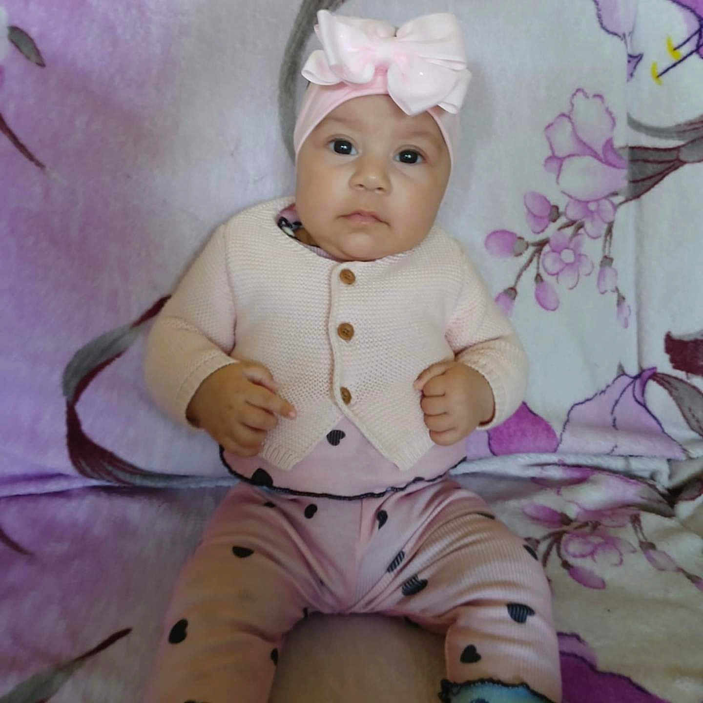 Seyda Melody is registered to the contest to win money with this photo: baby, blanket, bow, child, cozy, cute, expression, face, feet, floral_pattern, hands, headband, heart_pattern, indoor, infant, person, pink_clothing, portrait, sitting, socks