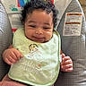 Kaziyah joined the competition — help win amazing prizes! baby, infant, curly_hair, bib, green_bib, baby_seat, monkey_design, rainbow, smiling, happy, cute, pink_blanket, indoor, child, young_child, face, portrait, comfort, seated, clothing