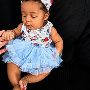 Kaziyah joined the competition — help win amazing prizes! baby, child, tutu, headband, blue, dress, sitting, couch, hand, finger, curious, cute, infant, portrait, clothing, foot, toes, skin, indoors, black_background