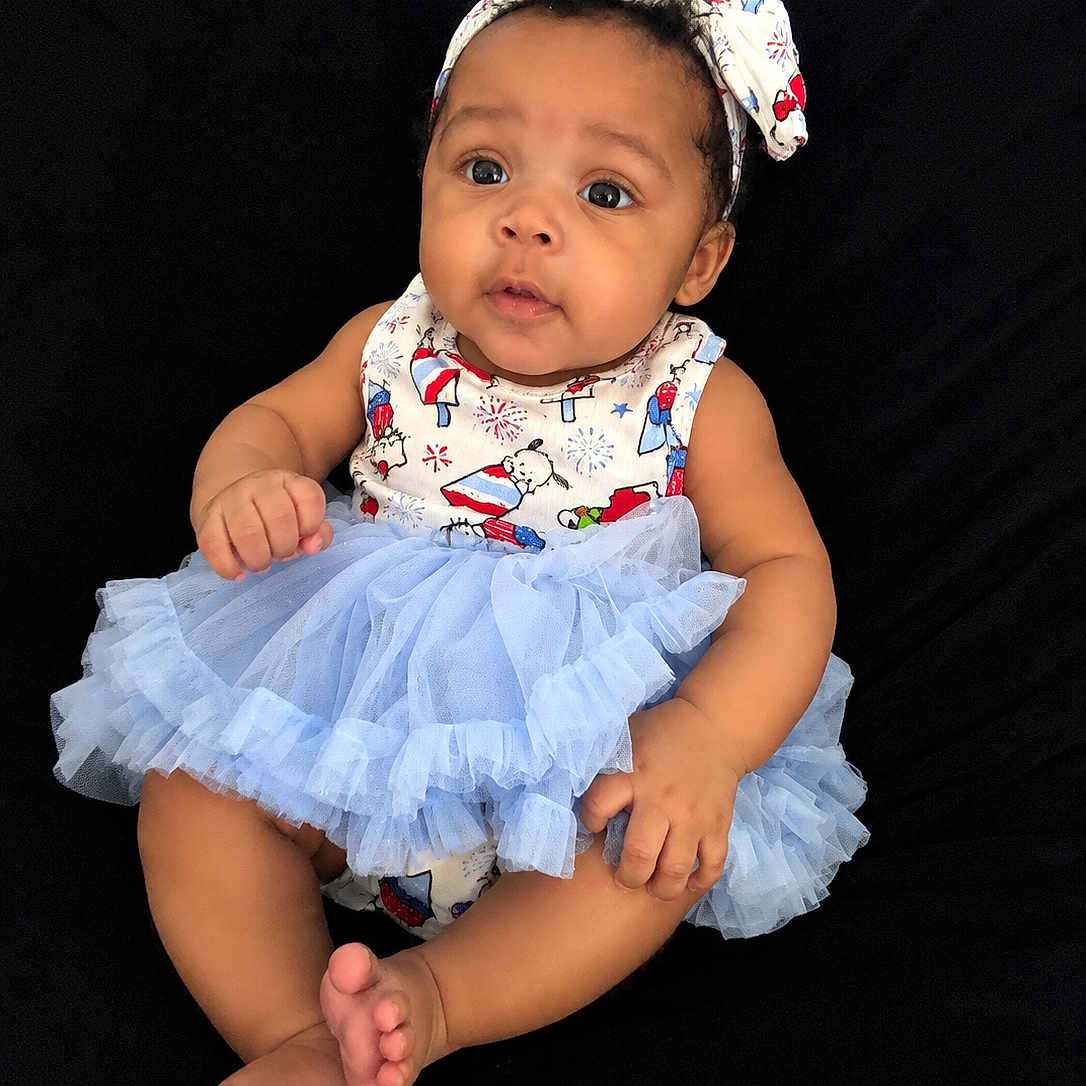 Kaziyah joined the competition — help win amazing prizes! baby, child, infant, tutu, headband, bow, dress, blue, curious, sitting, barefoot, cute, portrait, indoors, black_background, skin, smiling, person, young, adorable