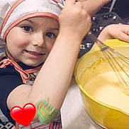 Yara participe au concours pour gagner de l'argent avec cette photo : apron, arm, baking, bowl, chef_hat, child, cooking, countertop, face, food_preparation, happy, indoor, kitchen, mixing, patterned_floor, person, playful, smile, whisk, young_child