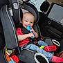 baby, car_seat, toy, red_shirt, blue_jeans, red_socks, child, infant, car_interior, seatbelt, smiling, happy, cute, safety, window, rain, headrest, seat, toddler, person