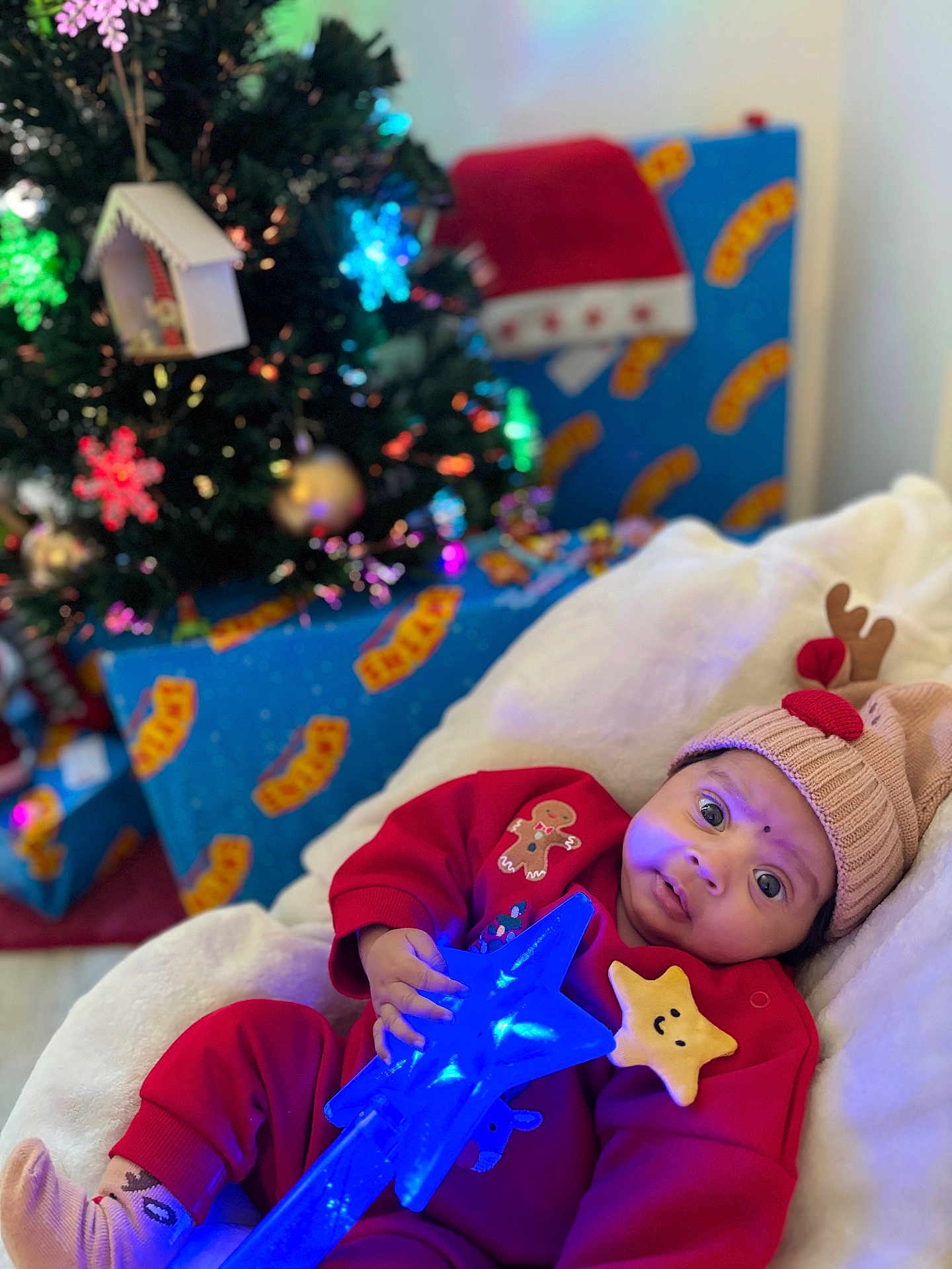 Ohena a rejoint le concours — aidez-le/la à gagner de superbes lots ! baby, child, christmas_tree, holiday, gift, present, red_clothing, reindeer_hat, star_wand, glowing_toy, blanket, indoor, festive, cute, smiling_star, decorations, ornament, christmas, holiday_lighting, cozy