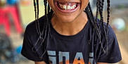 Jahïden a rejoint le concours — aidez-le/la à gagner de superbes lots ! child, smiling, braided_hair, black_tshirt, basketball_graphic, indoor, tiled_floor, holding_object, joyful, happy, portrait, person, casual_clothing, young, standing, closeup, face, teeth, expression, playful