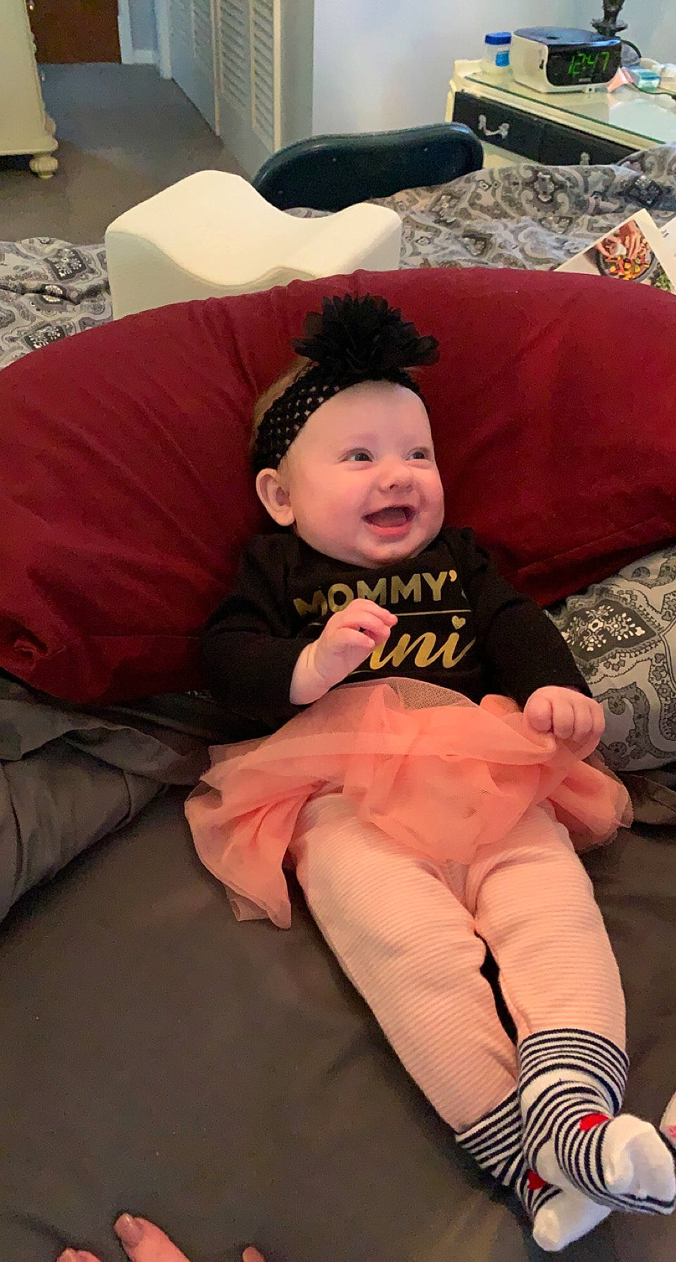 Ava is registered to the contest to win money with this photo: baby, baby_toddler_clothing, child, comfort, event, foot, fun, happy, headwear, human_leg, interaction, knee, lap, person, pink, sitting, skin, smile, sock, textile