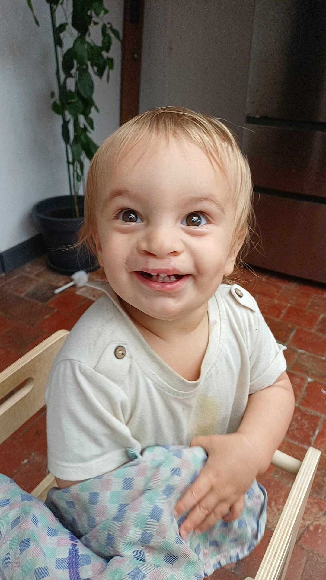 Izao a rejoint le concours — aidez-le/la à gagner de superbes lots ! toddler, child, smiling, happy, face, eyes, blanket, chair, wooden_chair, clothing, indoor, plant, pot, floor, tile_floor, kitchen, appliance, person, portrait, cute