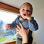 baby, child, smiling, hand, window, indoor, portrait, blue_shirt, checkered, happy, person, young_child, cute, face, fingers, clothing, holding, light, background, casual