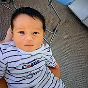 Zyed a rejoint le concours — aidez-le/la à gagner de superbes lots ! baby, infant, striped_clothing, person, indoor, carpet, furniture, metal, hand, holding, onesie, cute, young_child, portrait, face, head, expression, looking_up, comfort, cozy