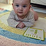 baby, infant, milestone_card, colorful_rug, indoor, cute, portrait, child, lying_down, soft_lighting, four_months, closeup, face, hands, floor, expression, young_child, home, cozy, toddler
