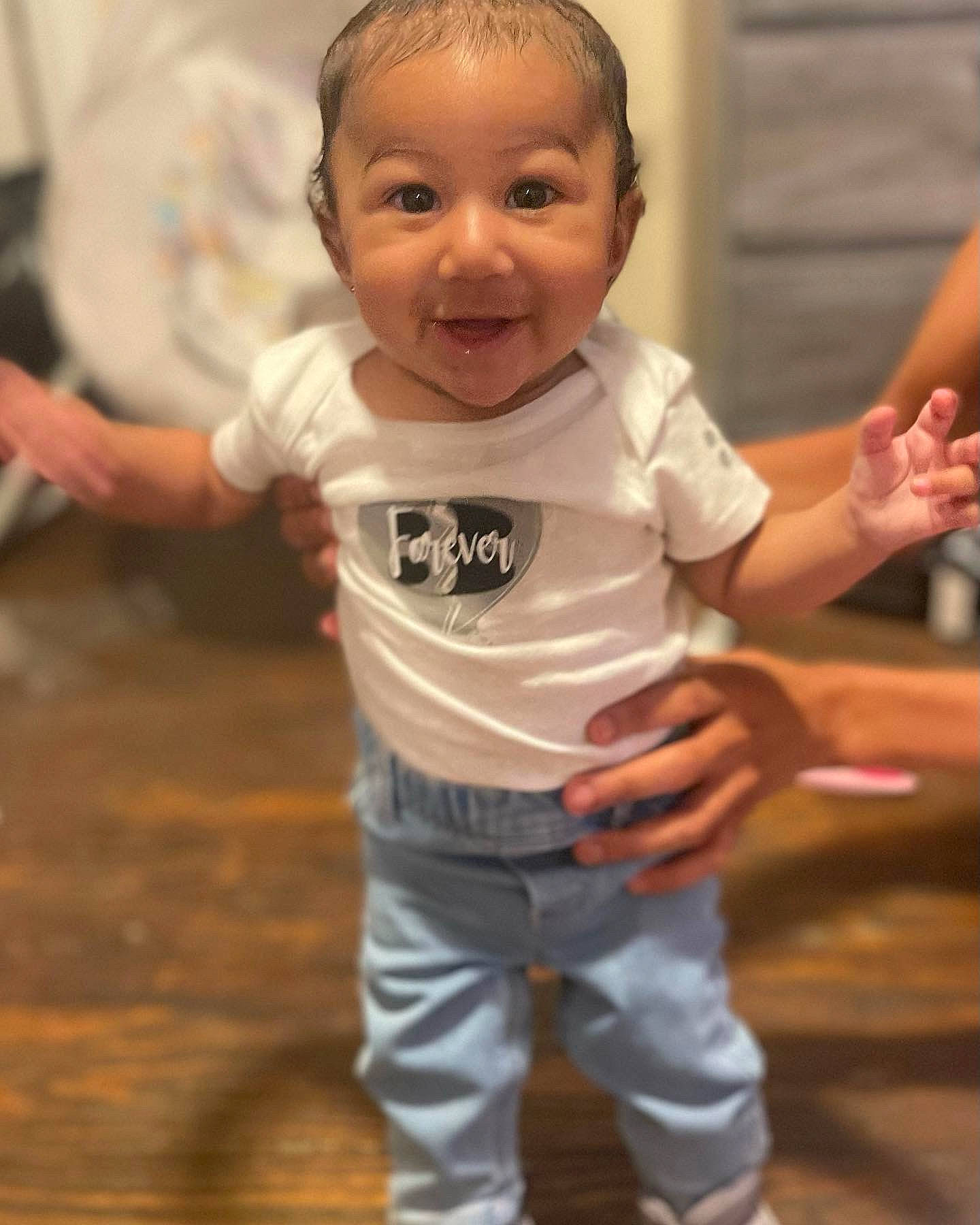 Arayah is registered to the contest to win money with this photo: baby, baby_toddler_clothing, cheek, child, finger, floor, flooring, gesture, hand, happy, joint, neck, nose, person, skin, sleeve, smile, standing, thumb, toddler