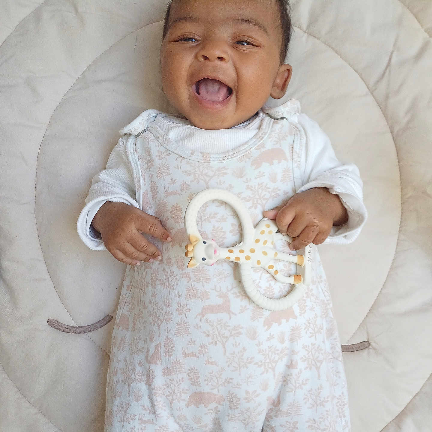 Amélia participe au concours pour gagner de l'argent avec cette photo : baby, smiling, infant, toy, giraffe, teether, cushion, blanket, white_clothing, onesie, happy, lying_down, cute, child, portrait, playful, indoors, soft_lighting, baby_girl, baby_boy