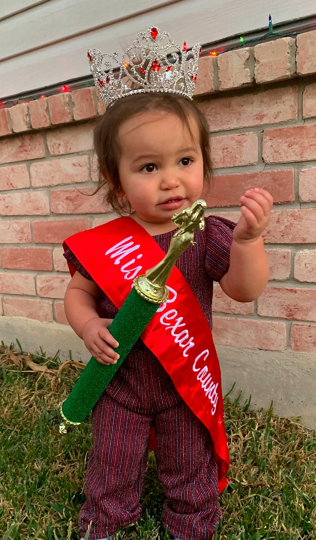 Gwendolyn joined the competition — help win amazing prizes! baby_toddler_clothing, brick, brickwork, costume_accessory, crown, fictional_character, grass_family, hair_accessory, headband, headpiece, overall, person, thumb, tiara, toddler
