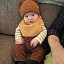 John joined the competition — help win amazing prizes! baby, child, hat, brown_clothing, bib, couch, indoor, person, cute, infant, face, sitting, hand, adult_arm, striped_shirt, black_socks, knit_hat, plush_blanket, home, portrait