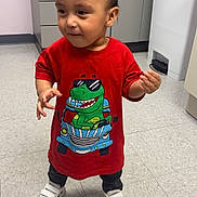 Natael joined the competition — help win amazing prizes! toddler, child, standing, portrait, smiling, red_shirt, dinosaur_shirt, sneakers, indoor, clinic, cabinet, floor_tiles, trash_bin, hands, short_hair, cute, casual_clothing, full_body, photograph, playful