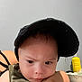 Eliel is registered to the contest to win money with this photo: toddler, child, face, cap, hat, camouflage, tank_top, indoor, person, portrait, hand, expression, serious, skin, eyebrows, closeup, headwear, baby, young_child, holding