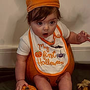 Hunter is registered to the contest to win money with this photo: baby, child, halloween, pumpkin, costume, hat, bib, orange, socks, leaves, autumn, holiday, cute, sitting, indoors, expression, holding, small_pumpkin, seasonal, celebration