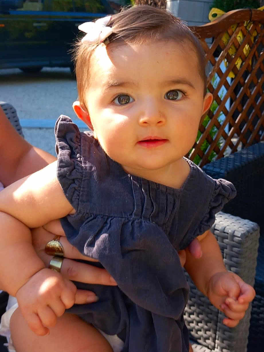 Valentina a rejoint le concours — aidez-le/la à gagner de superbes lots ! baby, child, outdoor, sunlight, dress, bow, hand, person, wicker_furniture, lattice, portrait, cute, infant, holding, skin, face, expression, summer, people, closeup