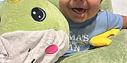 Lucas is registered to the contest to win money with this photo: baby, child, smiling, plush_toy, dinosaur, blue_shirt, indoor, window_blinds, cute, happy, face, person, soft_toy, seated, infant, closeup, light, home, joy, playful