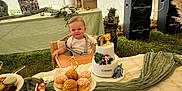 Côme a rejoint le concours — aidez-le/la à gagner de superbes lots ! baby, child, high_chair, cake, pastries, table, party, tent, decorations, photos, speakers, grass, food, celebration, smiling, cute, indoor, event, birthday, festive