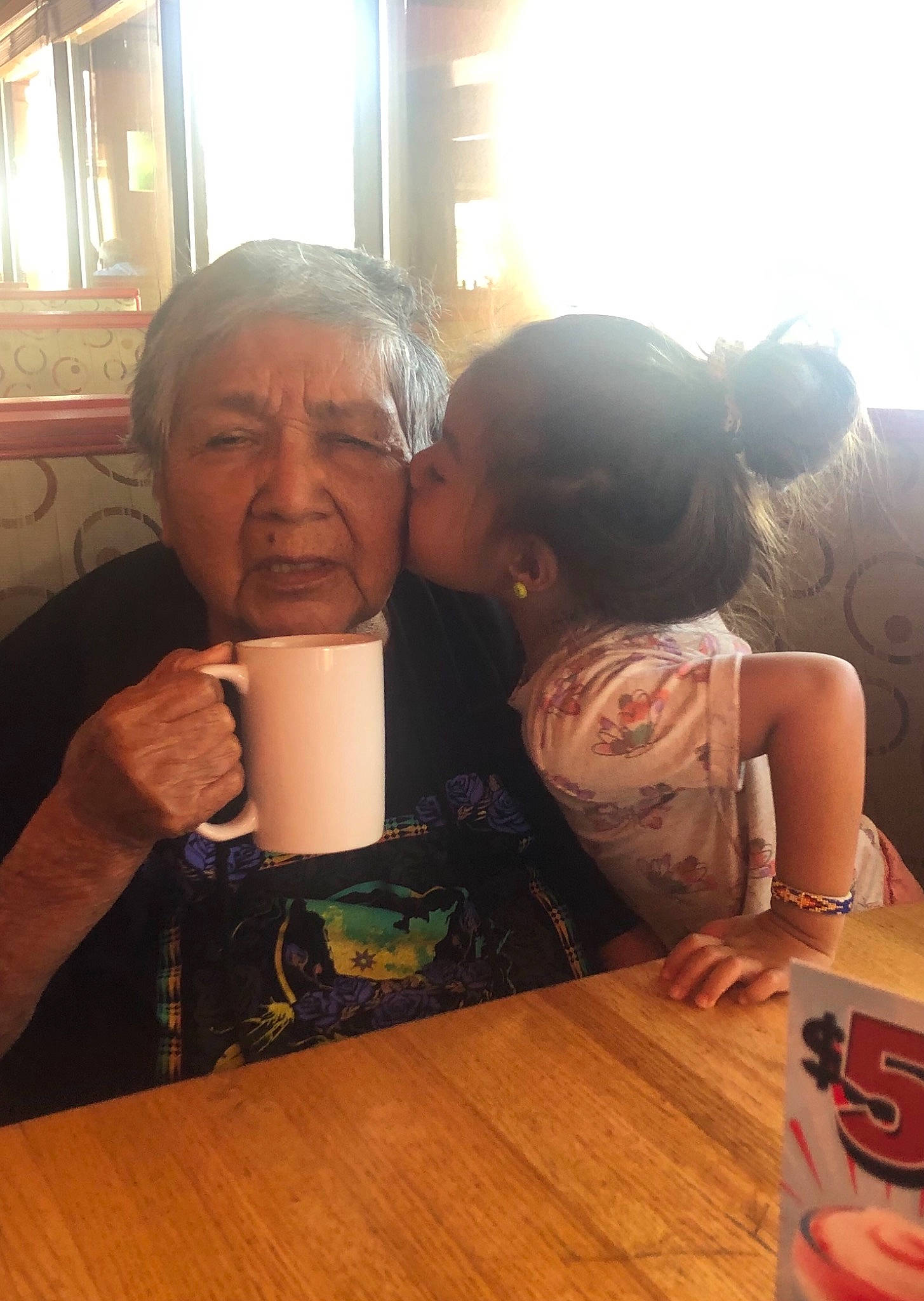 Tobie is registered to the contest to win money with this photo: cool, cup, drink, drinking, drinkware, event, eyewear, finger, flooring, fun, happy, kiss, leisure, morning, person, sitting, t_shirt, table, tableware, wood