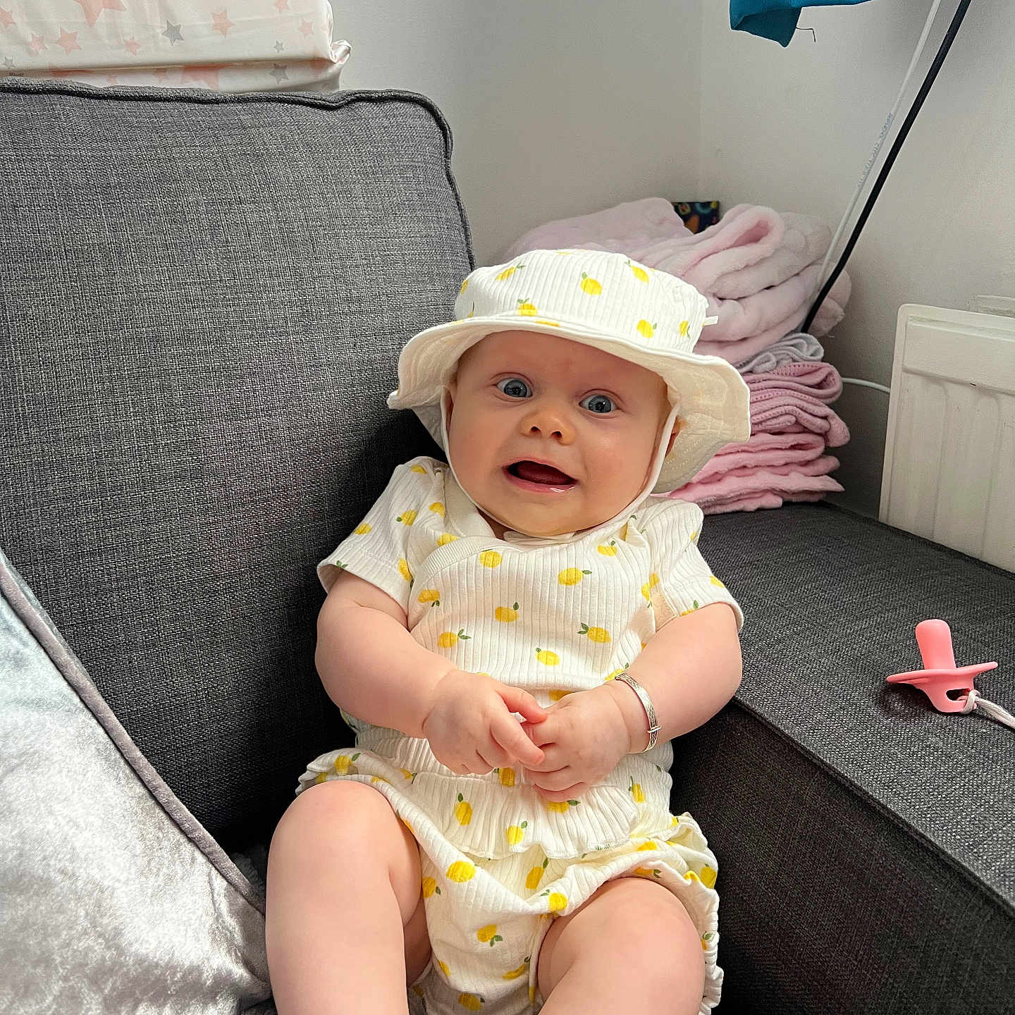 Azaylia joined the competition — help win amazing prizes! baby, blanket, bracelet, child, comfort, couch, cute, expression, grey_couch, hat, home, indoor, infant, lemon_pattern, pacifier, pink_blanket, plush, sitting, soft_fabric, white_clothing