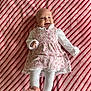baby, infant, smiling, floral_dress, white_tights, pink_slippers, striped_blanket, laying_down, happy, cute, child, portrait, indoors, soft_texture, cozy, small_hands, small_feet, head, face, clothing