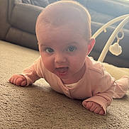 Alaiyah is registered to the contest to win money with this photo: baby, infant, carpet, pink_clothing, face, smiling, tongue_out, indoors, living_room, couch, window_blinds, curtains, child, person, home, floor, cute, happy, playful, tummy_time