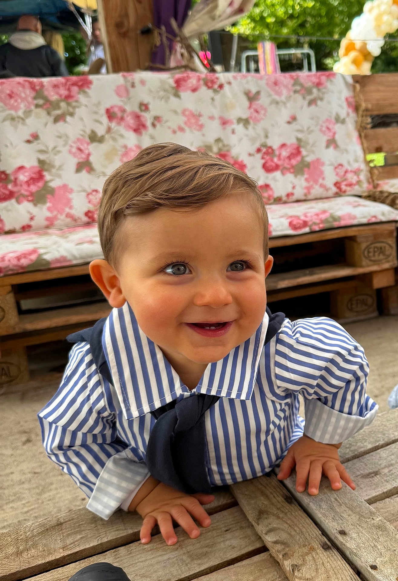Malo participe au concours pour gagner de l'argent avec cette photo : baby, child, smile, striped_shirt, navy_tie, crawling, wooden_deck, face, blue_eyes, hair, furniture, couch, floral_pattern, outdoor, daylight, cute, happy, person, portrait, infant