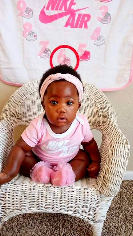 Charliebaby is registered to the contest to win money with this photo: baby, baby_products, baby_safety, baby_toddler_clothing, cheek, child, comfort, dress, fashion_accessory, happy, head, linens, magenta, pattern, person, pink, sitting, sleeve, smile, toddler