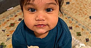 Saayan is registered to the contest to win money with this photo: toddler, child, face, eyes, blue_shirt, blanket, rug, sofa, indoor, floor, curly_hair, cute, looking_up, person, home, carpet, expression, leaning, young_child, portrait