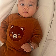 Noha participe au concours pour gagner de l'argent avec cette photo : baby, infant, child, brown_clothing, bear_design, bracelet, cushion, soft_fabric, portrait, indoors, cute, hand, face, expression, lying_down, young_child, comfortable, close_up, person, sleeping_area