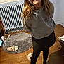 black_leggings, casual_clothing, child, closed_blinds, floor, girl, happy, home, hoodie, indoor, person, radiator, room, rug, slipper, smile, standing, window, wooden_floor, young