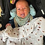 baby, bib, black_car_seat, blanket, car_seat, child, clothing, cute, fabric, face, happy, head, indoor, infant, patterned_blanket, person, seatbelt, sitting, smiling, tongue_out