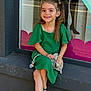 child, girl, green_dress, smile, sitting, toy, pacifier, window, street, reflection, sandals, hairclip, outdoor, building, concrete, daylight, happy, cute, portrait, person