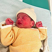 Mylo participe au concours pour gagner de l'argent avec cette photo : newborn, baby, infant, sleeping, hat, striped_clothing, yellow, white, knit_hat, fist, cozy, soft_texture, blanket, bed, cute, peaceful, indoors, portrait, child, resting