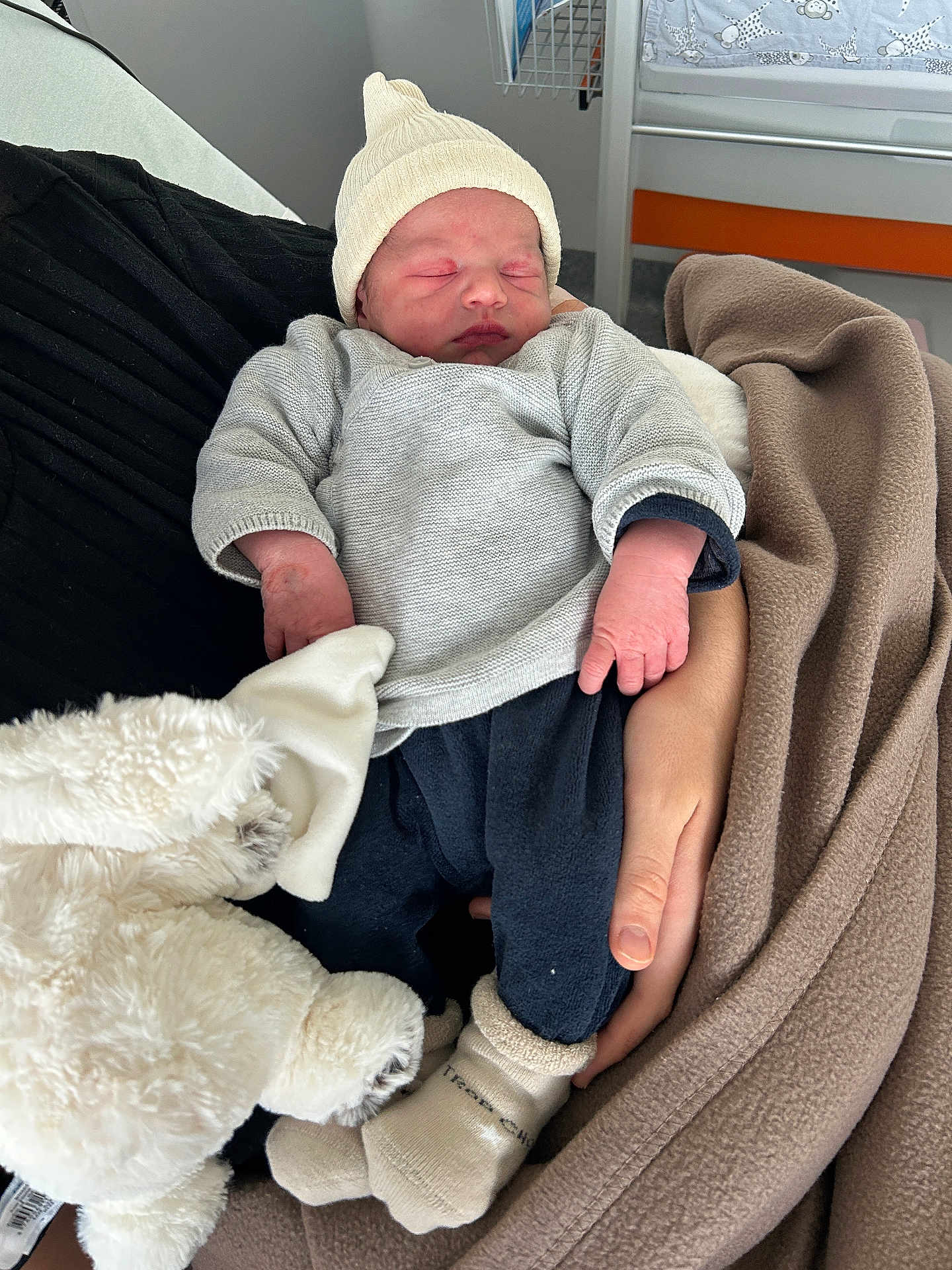 Mylo participe au concours pour gagner de l'argent avec cette photo : newborn, baby, sleeping, infant, hat, blanket, plush_toy, hand, clothing, hospital, nursery, bed, soft_toy, warm, cozy, resting, person, indoors, cute, child