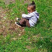 Sylvi joined the competition — help win amazing prizes! child, grass, outdoor, nature, sitting, hoodie, pants, shoes, side_view, greenery, sunlight, path, casual_clothing, young_child, alone, daytime, relaxing, calm, park, small_person
