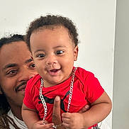 Eziah joined the competition — help win amazing prizes! baby, man, child, smile, red_shirt, chain, dreadlocks, holding, happy, indoor, portrait, person, cute, affection, family, skin, face, hand, casual_clothing, joy