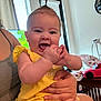 baby, child, smiling, happy, mohawk, yellow_clothing, hands, person, indoor, window, curtains, toy_car, adult_hand, furniture, living_room, skin, face, cute, playful, home