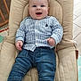 baby, baby_seat, baby_toys, blue_shirt, child, clothing, cushion, cute, denim_jeans, face, happy, indoor, infant, person, playmat, portrait, smiling, striped_shirt, striped_socks, wooden_floor
