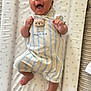 baby, infant, smiling, laughing, striped_clothing, teddy_bear_patch, changing_mat, star_pattern, cute, happy, lying_down, indoors, soft_lighting, newborn, child, person, apparel, foot, hand, portrait