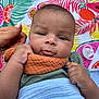 baby, infant, blanket, hand, pacifier, colorful, fruit_pattern, tropical, orange_cloth, green_shirt, face, cheeks, lying_down, outdoor, grass, closeup, expression, skin, person, child