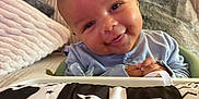 Camil is registered to the contest to win money with this photo: baby, smiling, face, infant, pillow, blanket, home, couch, playmat, pattern, clothing, child, person, indoor, cute, happy, young, portrait, soft, cozy