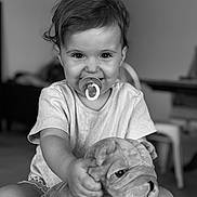 Nola a rejoint le concours — aidez-le/la à gagner de superbes lots ! toddler, child, pacifier, smile, plush_toy, dog_toy, indoor, black_and_white, portrait, happy, cute, short_hair, clothing, sitting, person, young_child, toy, face, expression, playful