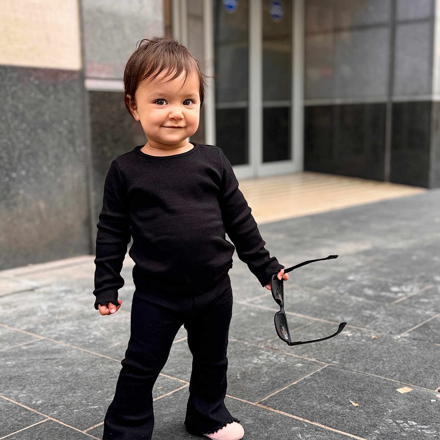 Naomi joined the competition — help win amazing prizes! black_clothing, casual, child, confident, cute, face, fashion, footwear, happy, outdoor, person, playful, sidewalk, smiling, standing, street, sunglasses, toddler, urban, young_child