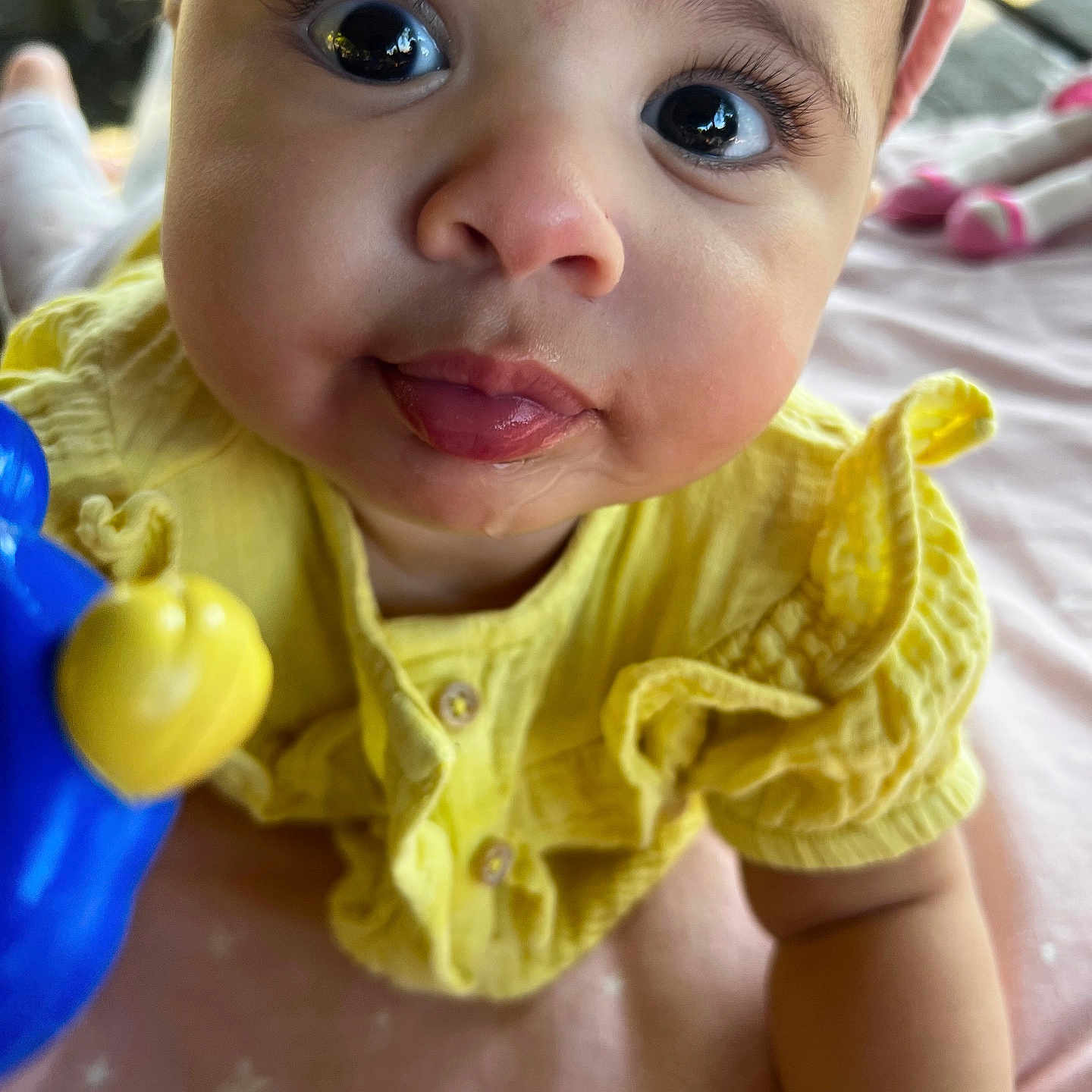 Niema a rejoint le concours — aidez-le/la à gagner de superbes lots ! baby, child, chubby_cheeks, close_up, curious_eyes, cute, doll, face, hand, indoors, infant, pink_blanket, playful, portrait, smiling, soft_lighting, tongue_out, toy, yellow_clothing, young_child